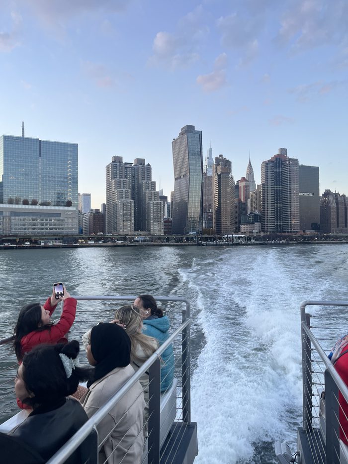 A tour group on a boat watching the Midtown Manhattan skyline at dusk