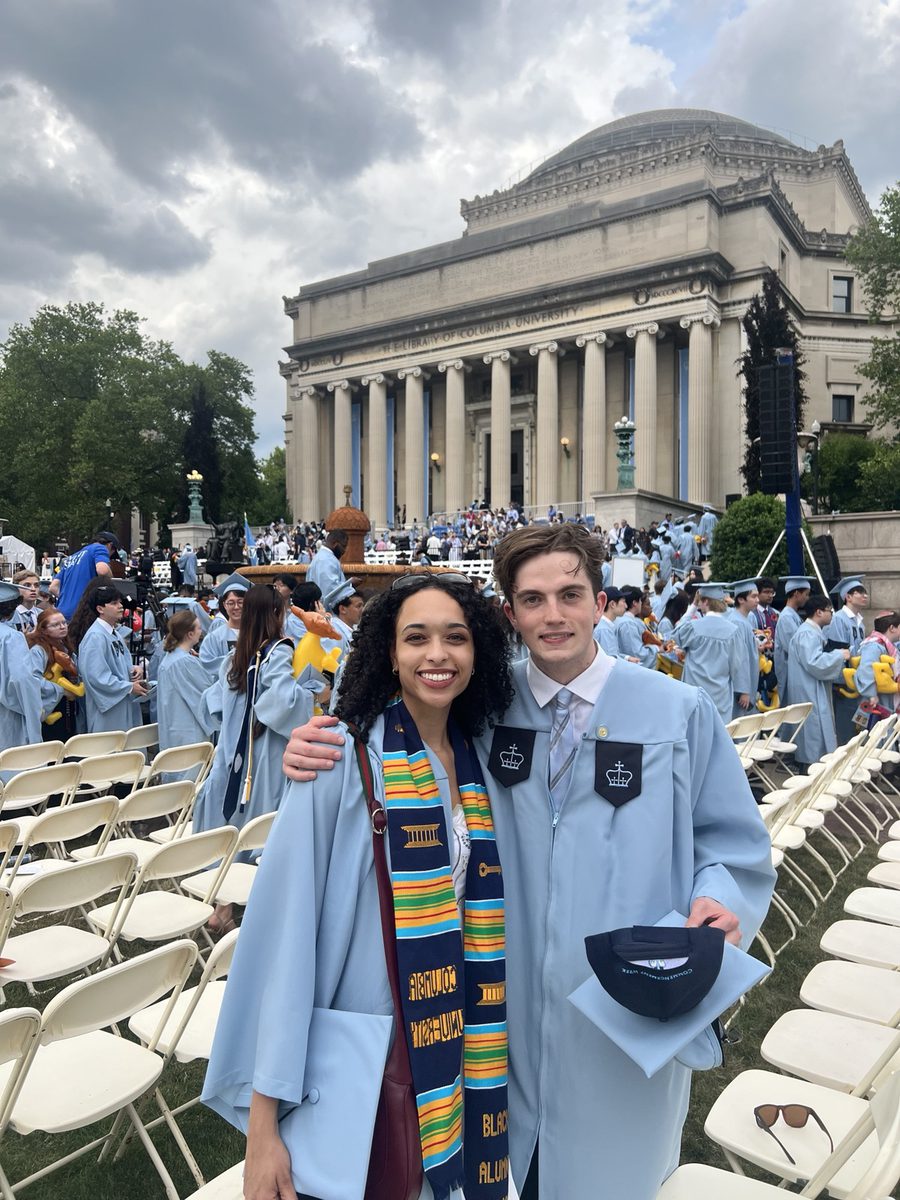 Two Columbia graduates in light blue gowns in front of Low Library on Commencement day